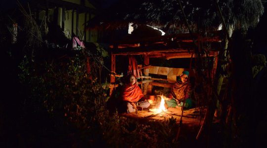 Nepalese women sit by a fire in a chhaupadi hut.